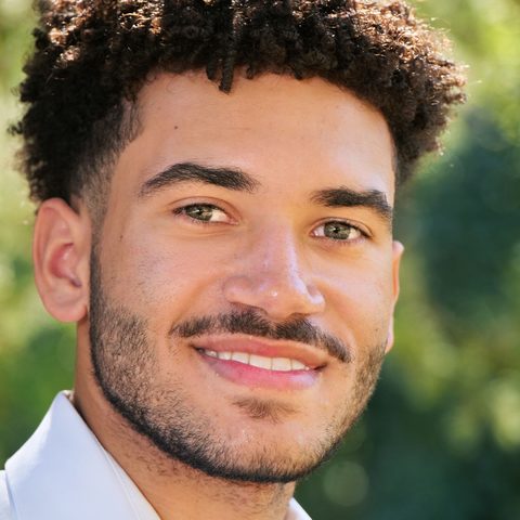 Student smiling outdoors in a white collared shirt